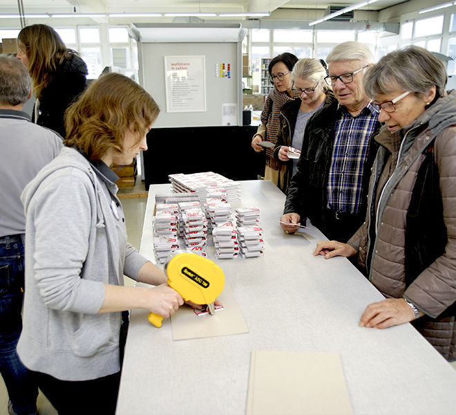 Janine Tremp befüllt die Jasskartenverpackung und klebt diese zusammen.